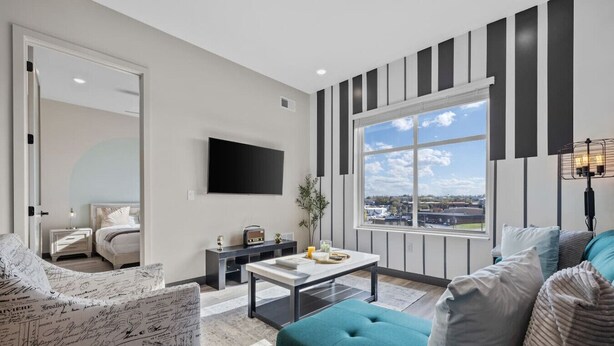 A modern living room with a large window, a flat-screen TV, a coffee table, and a sofa. - Urban Oasis 1BR - Quick Access to Downtown Nash! (Nashville)