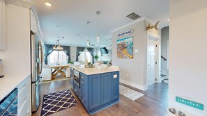 Un'ampia cucina con isola centrale, un'area pranzo con lampadario e un soggiorno con un grande quadro.