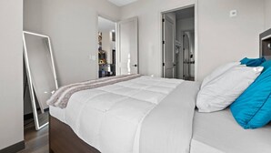 A bedroom with a large bed, a bedside table, and a mirror. There are doors leading to other rooms. - Trendy Oasis: 8 Min to Broadway, Sleeps 4! (Nashville)