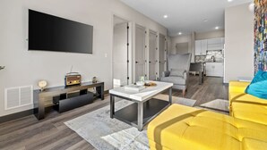 Ein modernes Wohnzimmer mit Flachbildfernseher, einem Vintage-Radio und einem gelben Sofa.