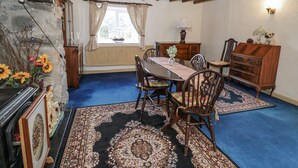 A dining room with a wooden table, chairs, and a blue carpet. - Old Post Office (Blaenau Ffestiniog)