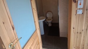 A wooden-framed bathroom with a toilet, sink, and a light fixture. - Cute cosy and chilled cabin in lahinch (Lahinch)