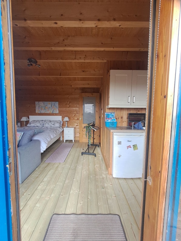 L’intérieur d’un chalet confortable, avec un lit, une petite cuisine et une salle de bain.