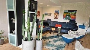 Ein modernes Wohnzimmer mit einer Eckcouch, einem Couchtisch und zwei Kakteen in Töpfen.