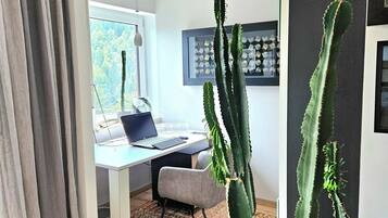 A modern office space with a desk, chair, and a large cactus plant.