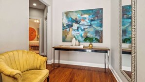 A modern interior with a yellow armchair, a large abstract painting, and a mirror on the wall. - Sunny 5BR Villa w/ Heated Pool & Courtyard Oasis (New Orleans)