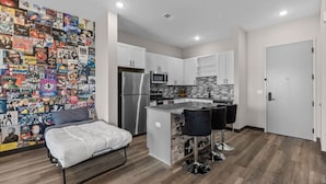 Ein modernes Apartment mit Küchenzeile, Essbereich und Wohnraum, dessen Wand mit Postern gestaltet ist.