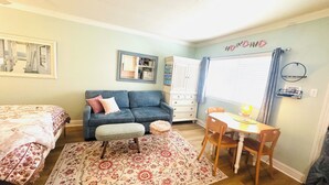 Une chambre à coucher avec un lit, un canapé bleu, une petite table avec une lampe, une chaise, un tapis et une armoire.