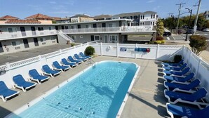 Un espace piscine avec des chaises longues bleues et une piscine.