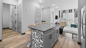 A modern kitchen with a central island, grey cabinetry, and a patterned wall art piece. - Quiet 1BR Apt - 8min to Broadway, Free Wifi! (Nashville)