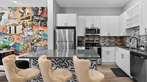 A modern kitchen with white cabinets, stainless steel appliances, and a central island with bar stools. - Quiet 1BR Apt - 8min to Broadway, Free Wifi! (Nashville)