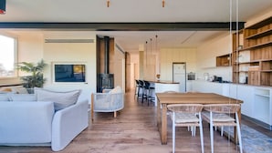 A modern living room with a sofa, a dining table with chairs, a TV, and a fireplace. - Shlomo Hamelekh Topaze (Tel Aviv)