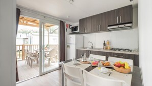 A compact kitchen with a dining area, a refrigerator, a microwave, and a gas stove. - Vacation village Jesolo Lodge Comfort for 5 persons (Lido di Jesolo)