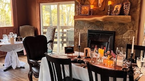 A dining area with a chandelier, stone fireplace, and antler decor.