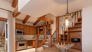 A kitchen with wooden cabinets, a stove, and a dining area with a round table and chairs. - Villa Valhalla | 9 - 2 Bedroom Loft Diamond (Vail)