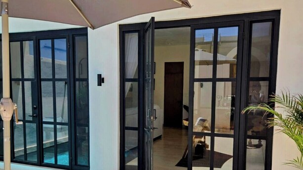 A poolside area with a lounge chair, a large umbrella, and a sliding glass door leading to an interior space. - 🌴Elegant Villa with Private Pool in Los Cabos☀️️ B.C.S, Mexico. (El Tezal)