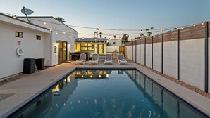 A swimming pool with lounge chairs, a patio area, and a building with a satellite dish. - Scottsdale Sunstone Villa, Modern 6BR w/ Private Pool & Spa, Walk to Old Town (Scottsdale)