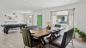 A dining area with a pool table, green door, and a large window with curtains. - Scottsdale Sunstone Villa, Modern 6BR w/ Private Pool & Spa, Walk to Old Town (Scottsdale)
