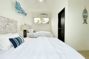 A hotel room with a bed, a wall art piece, a window, and a door.