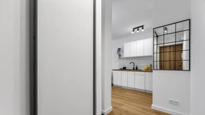 A modern kitchen with white cabinets, a wooden countertop, and a black backsplash. - Downtown Apt - Trams & Bus Nearby - by Rentujemy (Warszawa)