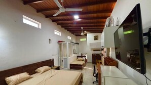 Ein Zimmer mit zwei Betten, einem Schreibtisch, einem Stuhl, einem Fernseher und einem Deckenventilator.