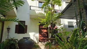 Ein Innenhof mit einem großen Blumentopf, Topfpflanzen und einem Gebäude mit Balkon.