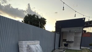 A rectangular hot tub with a stone waterfall feature, surrounded by a concrete deck and a metal fence. - Magnificent apartment in an upscale neighborhood (Imperatriz)