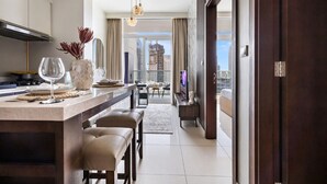 A modern kitchen with a dining area, a living room with a TV, and a balcony with a city view.