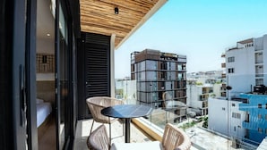Ein Balkon mit Korbstühlen und einem Tisch, mit Blick auf eine Skyline moderner Gebäude.