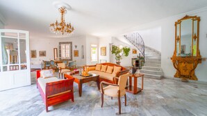A spacious living room with a marble floor, a large sofa, a coffee table, and a staircase leading to an upper level. - Authentique Villa Tunisoise Avec Piscine Marsa (La Marsa)