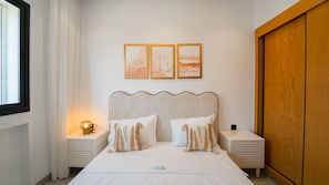 A neatly arranged bedroom with a bed, two bedside tables, a nightstand with a lamp, and a wooden wardrobe. - Rd Parcs Appartement Neuf aux Jardins De Carthage (Tunis)