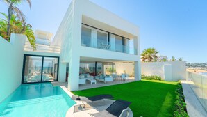A modern two-story house with a swimming pool, outdoor seating, and a view of the beach. - Villa Amaya Grand Luxe Face a la mer (La Marsa)