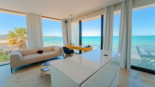 A modern room with a large desk, a sofa, and a view of the sea. - Villa Amaya Grand Luxe Face a la mer (La Marsa)