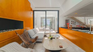 A modern living room with a large sofa, a coffee table, and a wooden accent wall. - Villa Amaya Grand Luxe Face a la mer (La Marsa)