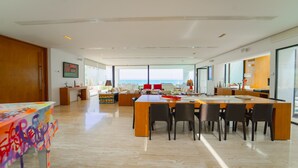 A spacious, modern living area with a large dining table, comfortable seating, and a view of the ocean. - Villa Amaya Grand Luxe Face a la mer (La Marsa)