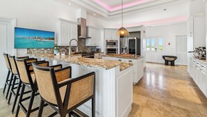 A spacious kitchen with a large island, white cabinetry, and modern appliances. - Oceanview Luxury 3 Bed Penthouse 5 minute walk to Grace Bay Beach (Providenciales)