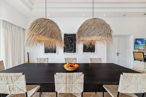 Un coin repas avec une table en bois foncé, des chaises en osier et un centre de table composé d’un panier de fruits.