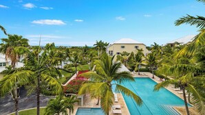 A resort with a large pool, palm trees, and a view of the ocean. - Oceanview Luxury 3 Bed Penthouse 5 minute walk to Grace Bay Beach (Providenciales)