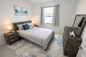 Une chambre à coucher comprenant un lit, des tables de chevet, une commode, un miroir et deux tableaux accrochés au mur.