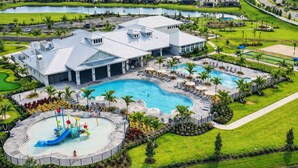 Ein Resort mit großem Schwimmbad, einer Wasserrutsche und einem Golfplatz im Hintergrund.