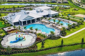 Un resort con una amplia piscina, un tobogán acuático y un campo de golf al fondo.