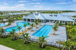 Un resort con una amplia piscina, varias edificaciones con techos azules y vistas a un lago.