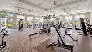 Un gimnasio amplio con diversos equipos de ejercicio, ventanas grandes y un diseño moderno y limpio.
