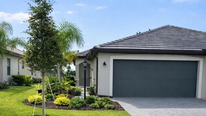 A residential driveway leading to a garage, surrounded by well-maintained grass and small trees. - Modern Villa New Build & Furniture/Resorts Amenities (Bradenton)