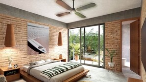 Une chambre moderne avec un grand lit, un ventilateur de plafond, un mur en briques et une vue sur la verdure.