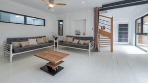 Un salon moderne avec un canapé, une table basse et un escalier.