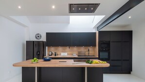 Une cuisine moderne dotée d’un îlot central, de meubles de couleur noire et d’une verrière.