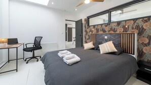 Une chambre à coucher moderne avec un grand lit, un bureau et une chaise.