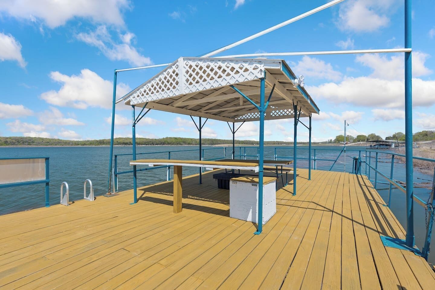 A wooden deck with a covered seating area, a table, and a bench.