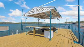 A wooden deck with a covered seating area and a view of the water.